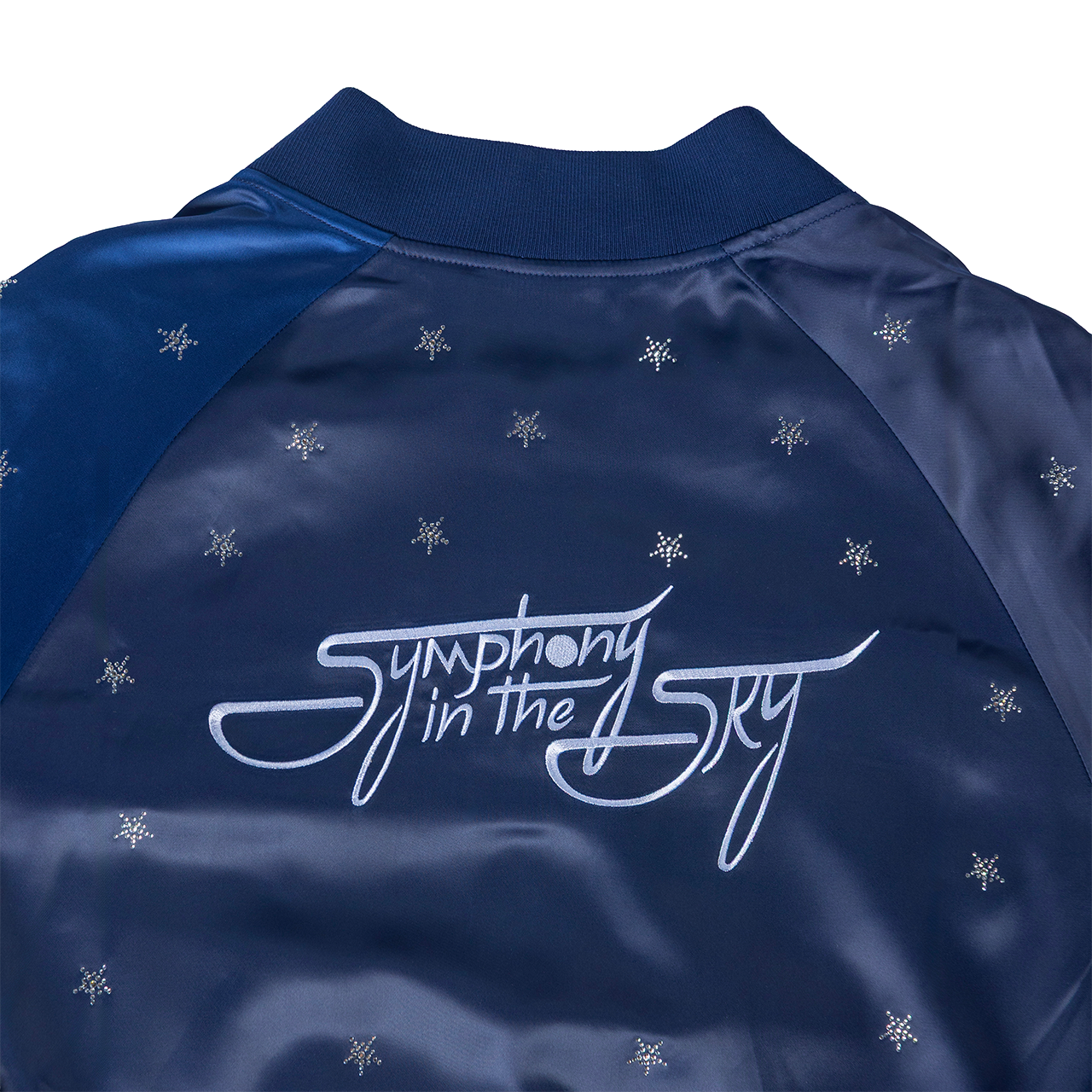 Navy blue jacket with 'Symphony in the Sky' logo and snowflake patterns on a white background