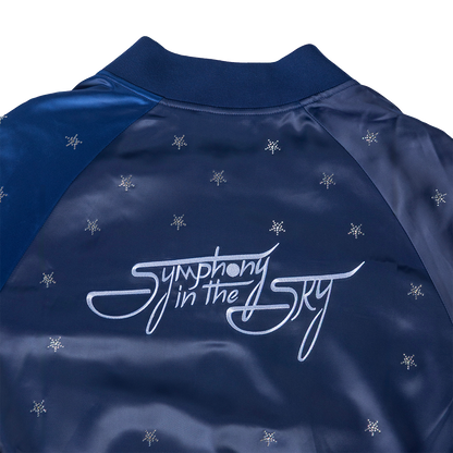 Navy blue jacket with 'Symphony in the Sky' logo and snowflake patterns on a white background